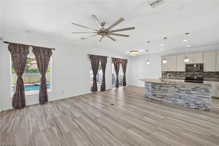 Spacious open-concept living area featuring wood-finish flooring, a contemporary ceiling fan, and recessed lighting