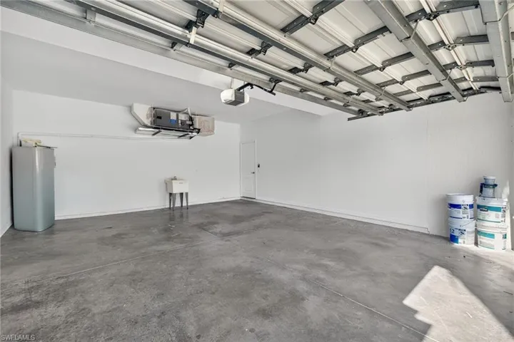 Spacious garage featuring a concrete floor, white walls, and an overhead garage door mechanism