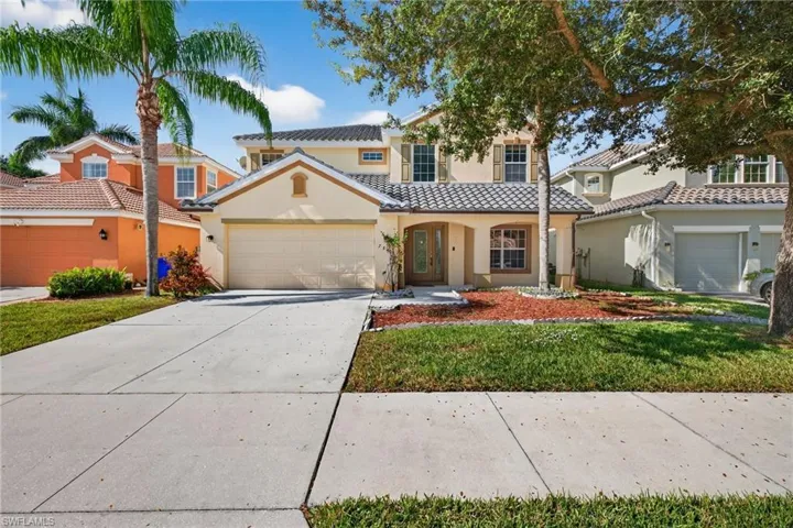 Contemporary stucco home featuring a tiled roof, an attached two-car garage, a concrete driveway, and mature landscaping