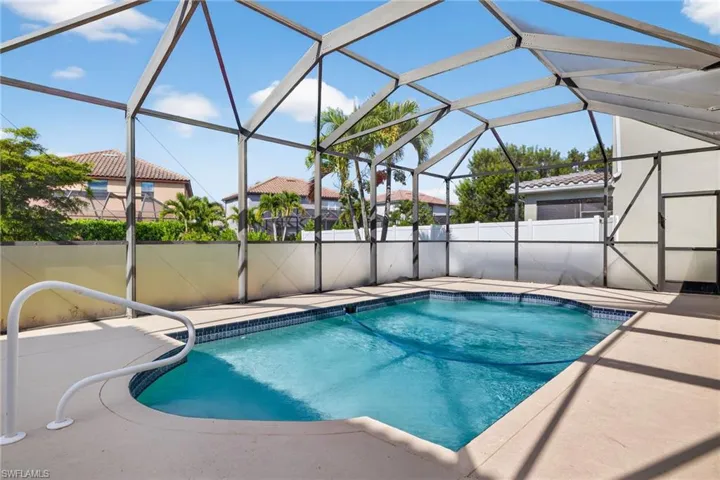 Screened enclosure with a rectangular swimming pool featuring a curved entry and integrated handrail
