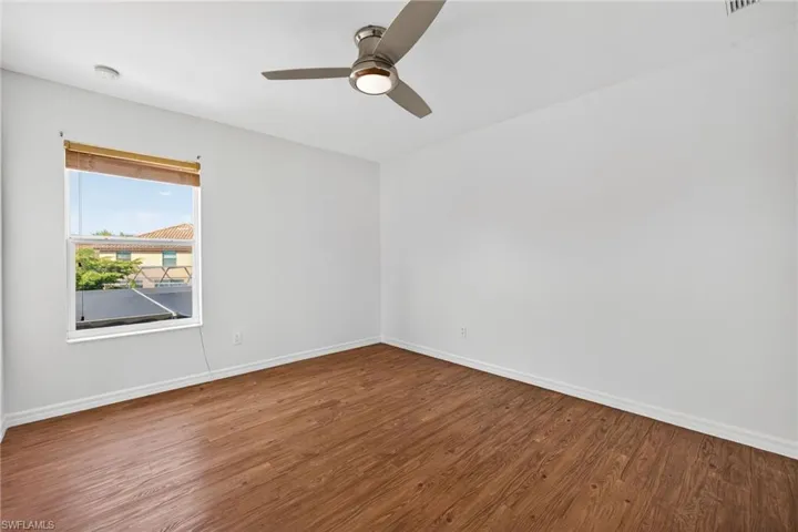 Room featuring wood-finish flooring, white walls, and a modern ceiling fan with integrated lighting