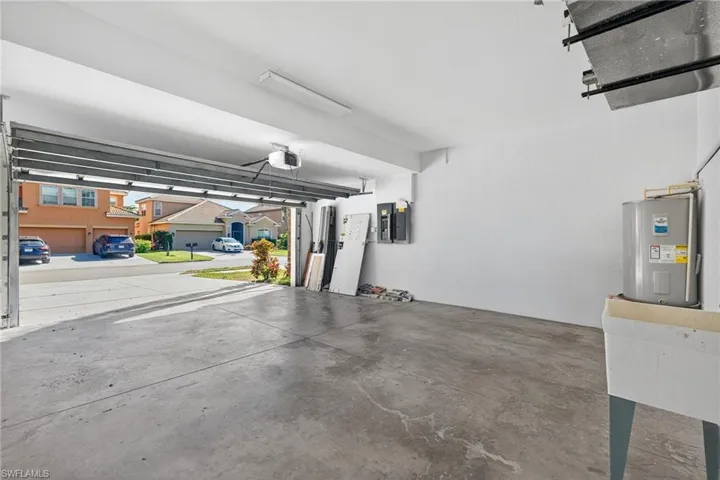 Spacious garage with concrete flooring, overhead lighting, and an automatic garage door opener