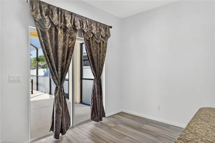 Sliding glass door opening to an outdoor screened enclosure, featuring wood-finish flooring and a neutral color palette