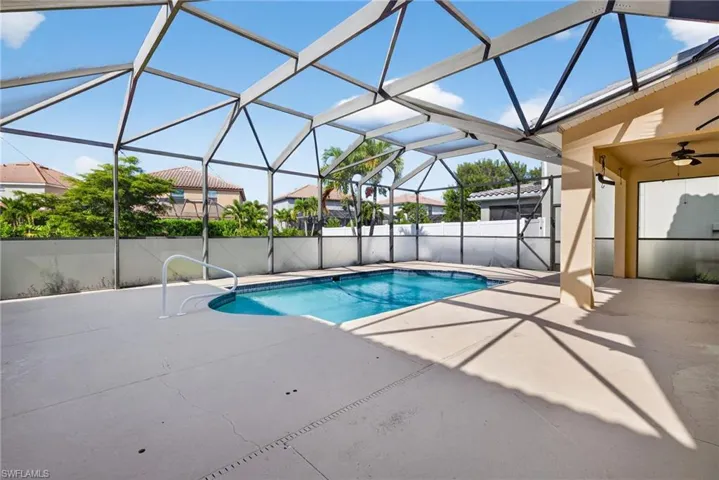 Screened-in pool deck featuring a freeform swimming pool with integrated handrails