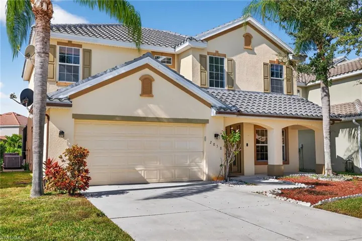 Mediterranean-inspired stucco exterior featuring a two-car garage, arched entryways, and a concrete tile roof