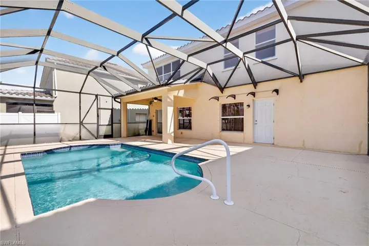 Screened-in outdoor living space featuring a swimming pool with integrated steps, a spacious concrete pool deck, and an attached covered patio with a ceiling fan