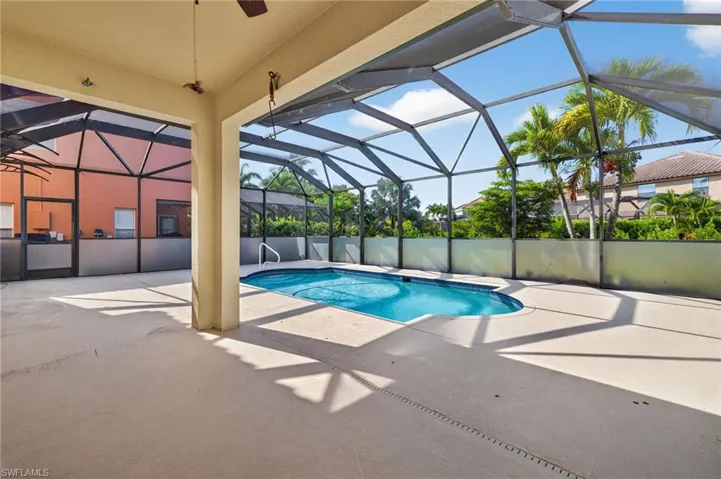 Screened enclosure featuring an in-ground swimming pool, ample patio space, and mature tropical landscaping