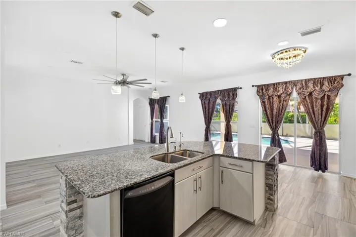 Kitchen island with granite countertop, double basin sink, and integrated dishwasher