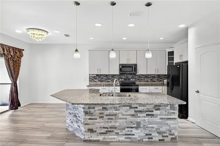 Kitchen island featuring a granite countertop and stacked stone base