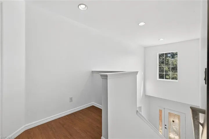 Upper landing with wood-finish flooring, white baseboards, and recessed lighting