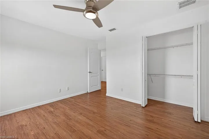 Bright interior room featuring wood-finish flooring, white walls, and a ceiling fan with integrated lighting