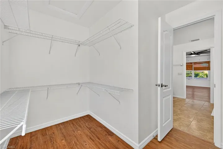 Walk-in closet featuring built-in wire shelving, white baseboards, and wood-finish flooring