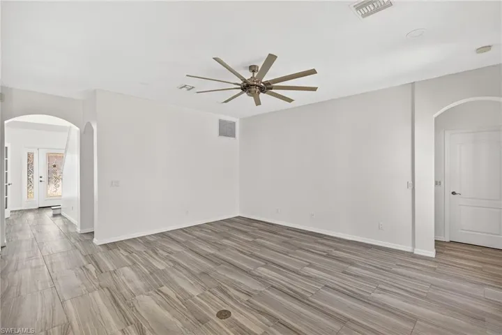 Spacious interior featuring wood-finish tile flooring, a contemporary ceiling fan, recessed lighting, and arched doorways
