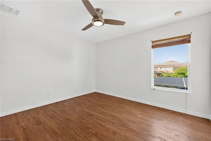 Room with wood-finish flooring, white walls, and a window with natural light