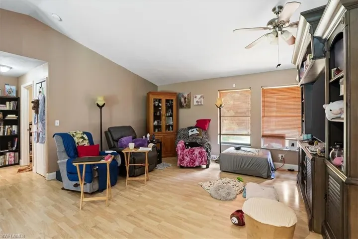 Living room featuring vaulted ceiling, light wood-style flooring, and a ceiling fan