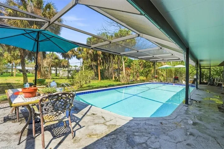 Outdoor pool with a lanai, a patio area, a sunroom, and outdoor dining space