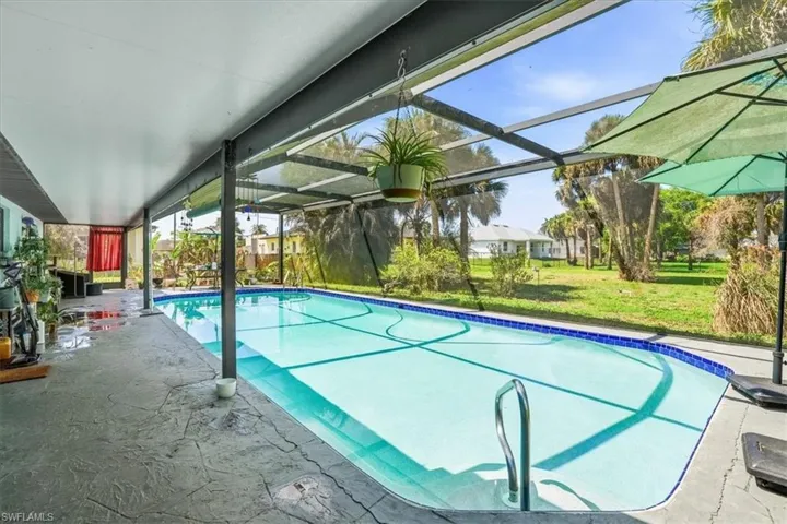Outdoor pool with a patio, a sunroom, a lanai, and a lawn