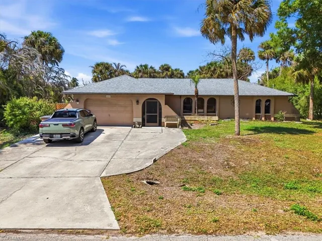 Single story home with an attached garage, concrete driveway, a front lawn, and stucco siding