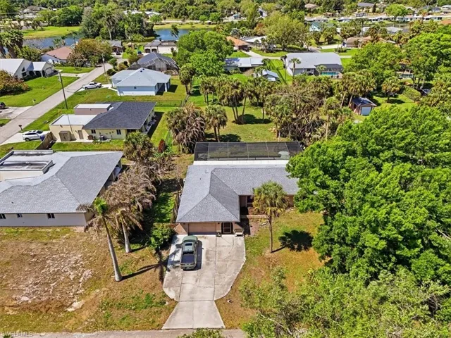 Aerial view of residential area with a nearby body of water and a tree filled landscape