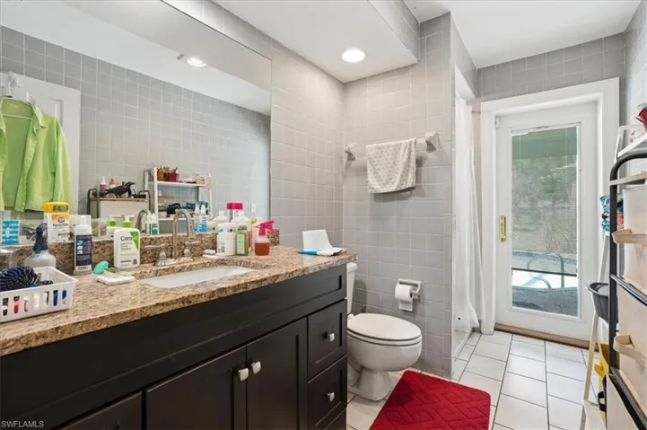 Full bathroom with tile walls, vanity, light tile patterned flooring, and recessed lighting