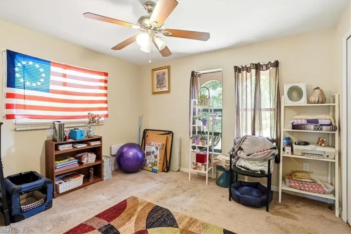 Exercise room featuring light colored carpet and a ceiling fan