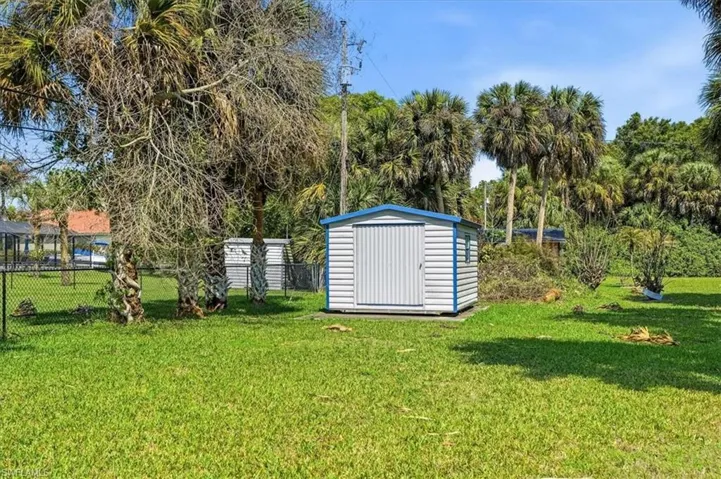 Fenced yard featuring a storage shed and view of wooded area