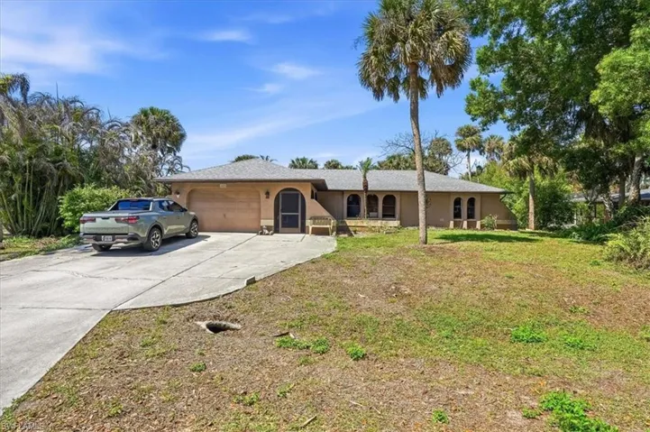 Single story home featuring an attached garage, concrete driveway, stucco siding, and a front lawn