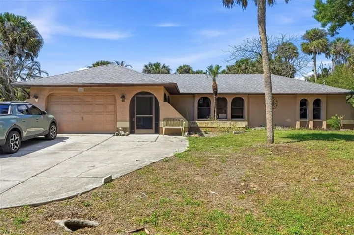 Single story home featuring an attached garage, stucco siding, driveway, a front lawn, and roof with shingles