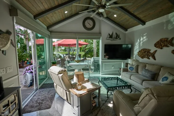 Tiled living room with wooden ceiling, beamed ceiling, ceiling fan, and high vaulted ceiling