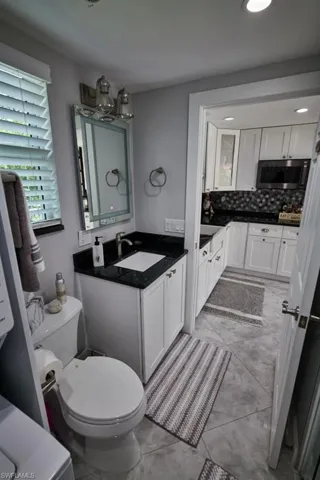Bathroom with decorative backsplash, vanity, and toilet