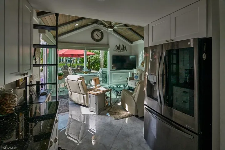Kitchen featuring lofted ceiling with beams, wood ceiling, ceiling fan, and stainless steel fridge with ice dispenser