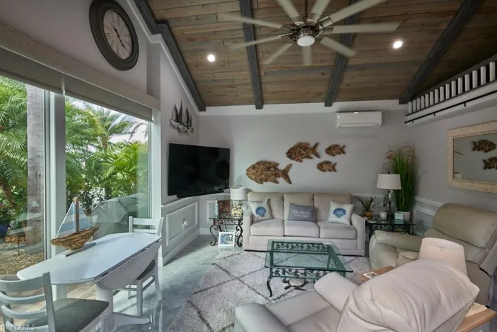 Living room with wood ceiling, high vaulted ceiling, an AC wall unit, beamed ceiling, and ceiling fan