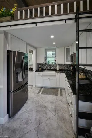 Kitchen featuring stainless steel appliances, sink, decorative backsplash, and white cabinetry
