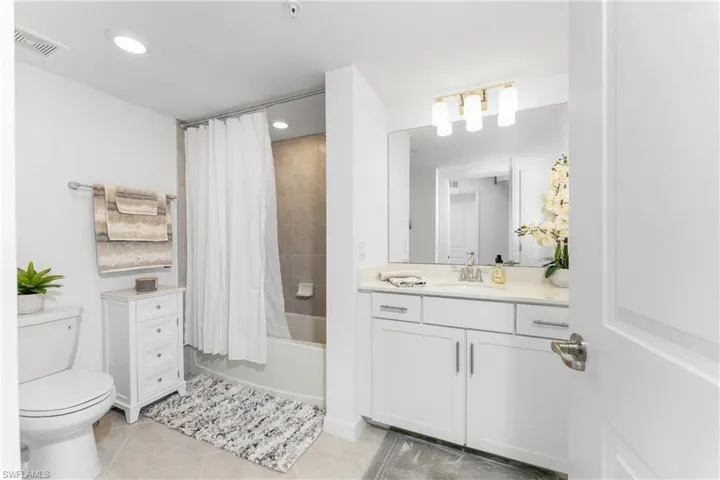 Bathroom with shower / bathtub combination with curtain, vanity, light tile patterned floors, and recessed lighting