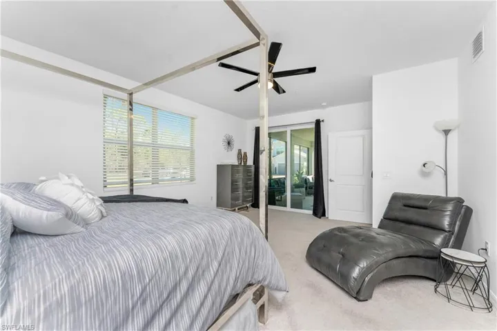 Bedroom with light carpet, multiple windows, a ceiling fan, and access to exterior