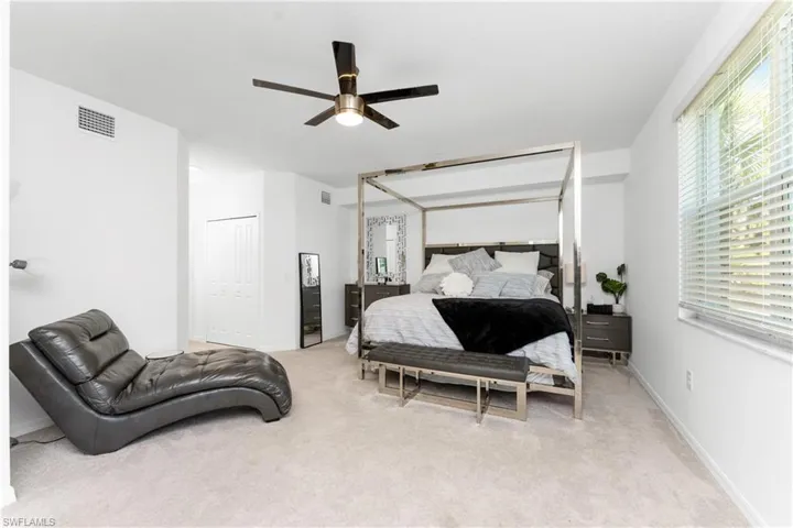 Bedroom featuring light colored carpet, a ceiling fan, and a closet