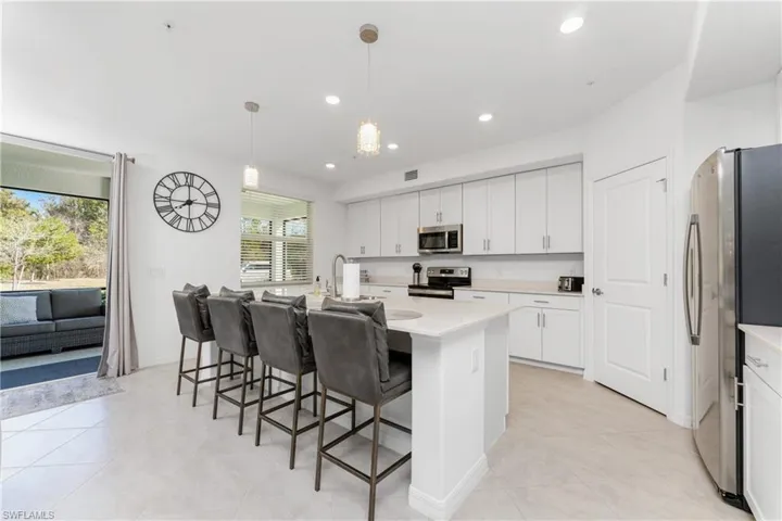 Kitchen featuring a kitchen island with sink, stainless steel appliances, a kitchen bar, and white cabinets