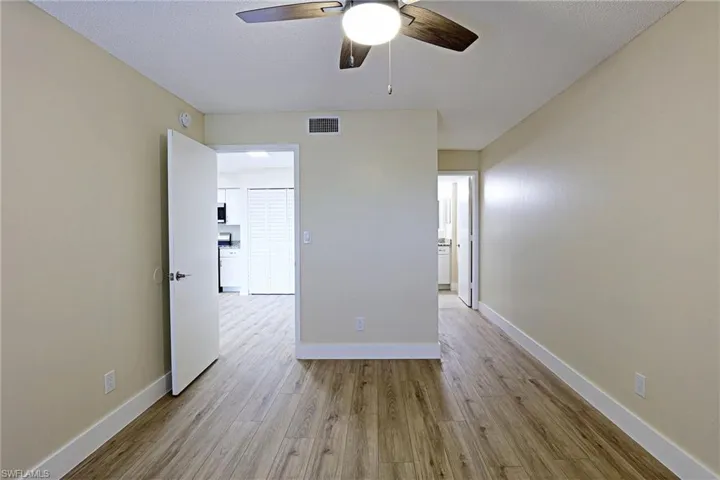 Unfurnished room featuring light wood-type flooring, a ceiling fan, and a textured ceiling