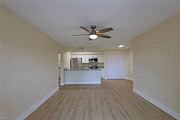Kitchen with light wood finished floors, appliances with stainless steel finishes, white cabinetry, open floor plan, and a ceiling fan