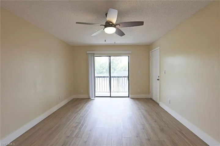 Unfurnished room with light wood finished floors, a textured ceiling, and a ceiling fan