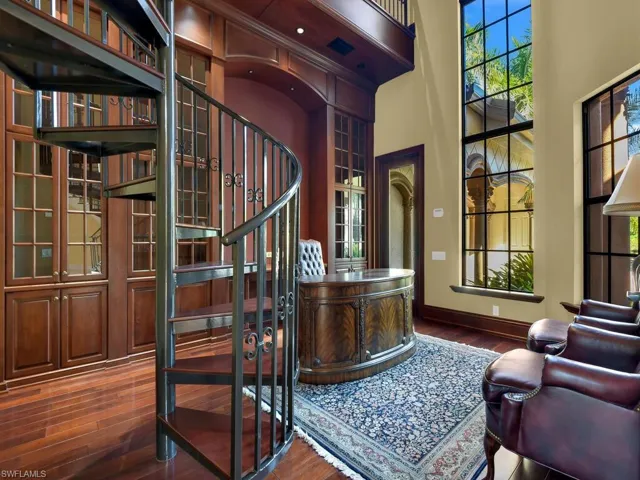 Home office with a towering ceiling and dark wood finished floors