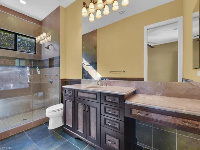 Bathroom featuring vanity, a shower stall, tile walls, and wainscoting