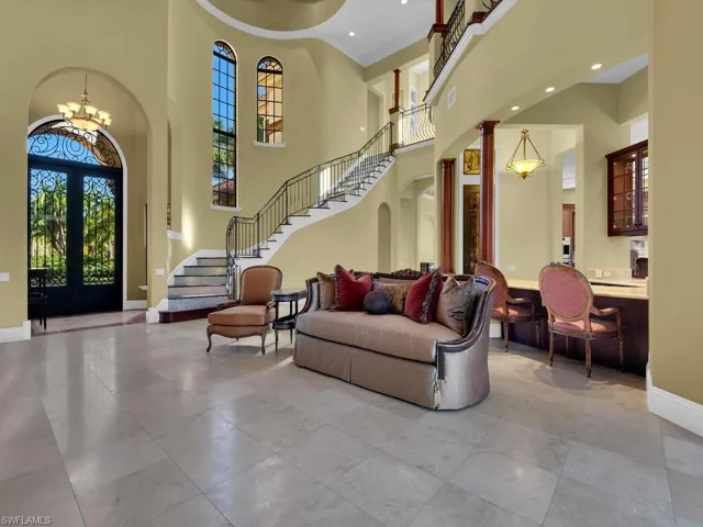 Foyer featuring french doors, a chandelier, stairway, a towering ceiling, and arched walkways