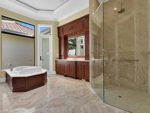 Bathroom with vanity, a stall shower, crown molding, a bath, and light marble finish floors