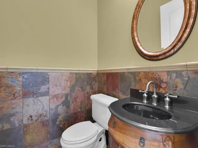 Bathroom with vanity, wainscoting, and tile walls