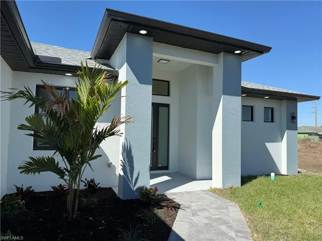 Doorway to property with stucco siding and a yard