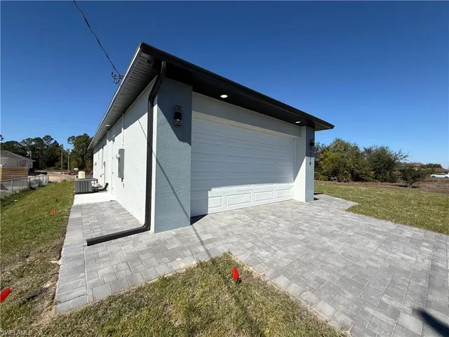 View of home's exterior with a yard, stucco siding, and decorative driveway