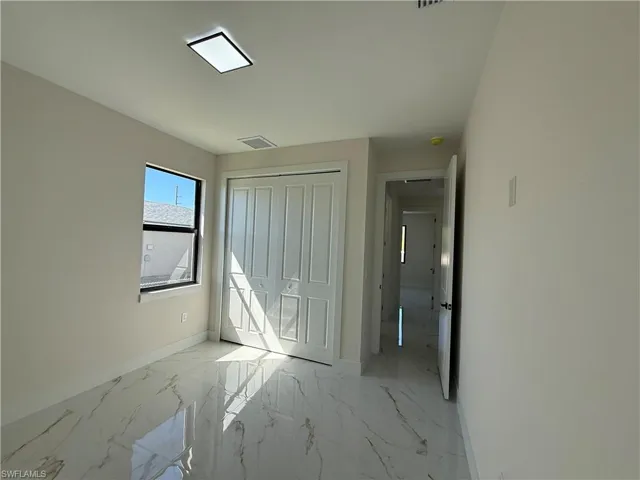 Unfurnished bedroom with light marble finish flooring and a closet
