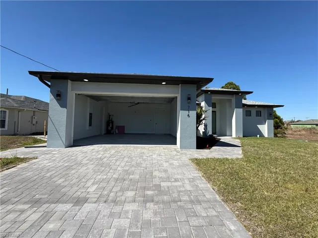 View of front of property with a front lawn, decorative driveway, and stucco siding