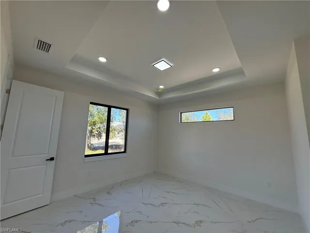 Spare room featuring light marble finish flooring, recessed lighting, and a tray ceiling